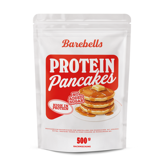 White pouch of Barebells Protein Pancakes, a 500 g high-protein baking mix, with red branding. The front shows the “Protein Pancakes” title on a red background, “High in protein” and “No added sugar” badges, and an illustration of a stack of pancakes topped with butter and syrup on a white plate.
